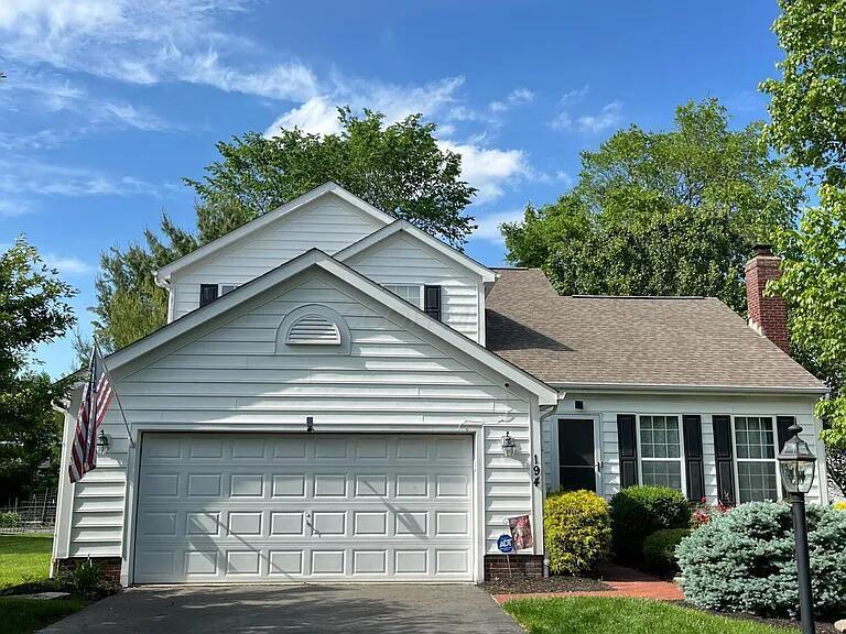 194 Stamford Dr, Powell, OH 43065 - view of front of property featuring driveway, a garage, a chimney, and a shingled roof