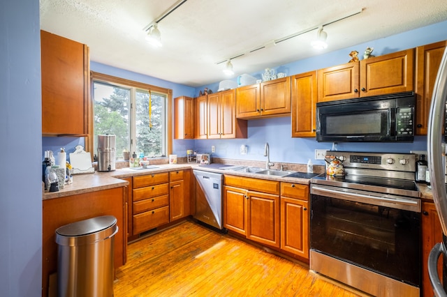 4842 State Route 734, Jeffersonville, OH 43128 - kitchen with appliances with stainless steel finishes, a sink, brown cabinets, light wood-style flooring, and track lighting