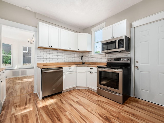 534 Berkeley Rd, Columbus, OH 43205 - kitchen with appliances with stainless steel finishes, butcher block countertops, a sink, light wood-style floors, and a textured ceiling