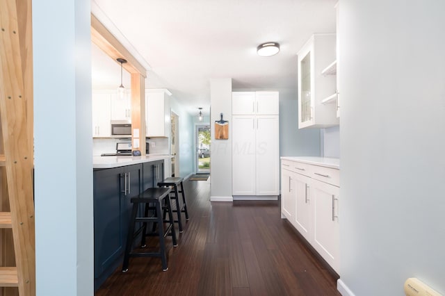 11177 Sassafrass Rd, Lakeview, OH 43331 - kitchen featuring stainless steel microwave, dark wood-type flooring, white cabinets, a kitchen breakfast bar, and light countertops