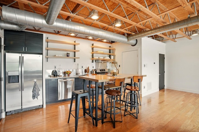 956 N High St Unit 2W, Columbus, OH 43201 - kitchen featuring appliances with stainless steel finishes, open shelves, light wood-style floors, and dark cabinets