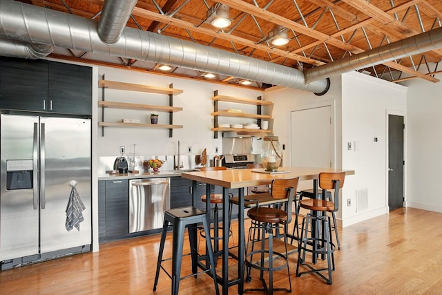 956 N High St Unit 2W, Columbus, OH 43201 - kitchen with appliances with stainless steel finishes, light wood-style floors, open shelves, dark cabinets, and light countertops
