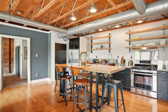 956 N High St Unit 2W, Columbus, OH 43201 - kitchen featuring stainless steel appliances, open shelves, light countertops, and light wood-style floors