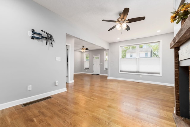 71 Market St, Carroll, OH 43112 - unfurnished living room with ceiling fan, a brick fireplace, baseboards, and light wood-style flooring