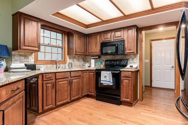 248 Academy Woods Dr, Columbus, OH 43230 - kitchen with black appliances, backsplash, light wood finished floors, light stone counters, and brown cabinets