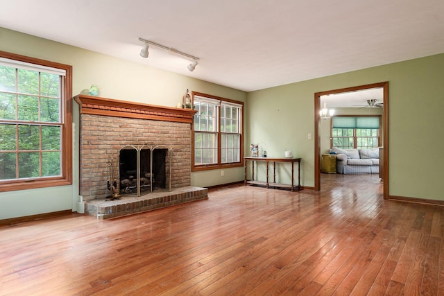248 Academy Woods Dr, Columbus, OH 43230 - unfurnished living room featuring a fireplace, hardwood / wood-style flooring, baseboards, and rail lighting