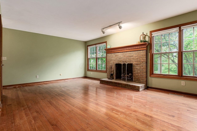 248 Academy Woods Dr, Columbus, OH 43230 - unfurnished living room with wood-type flooring, a brick fireplace, baseboards, and rail lighting