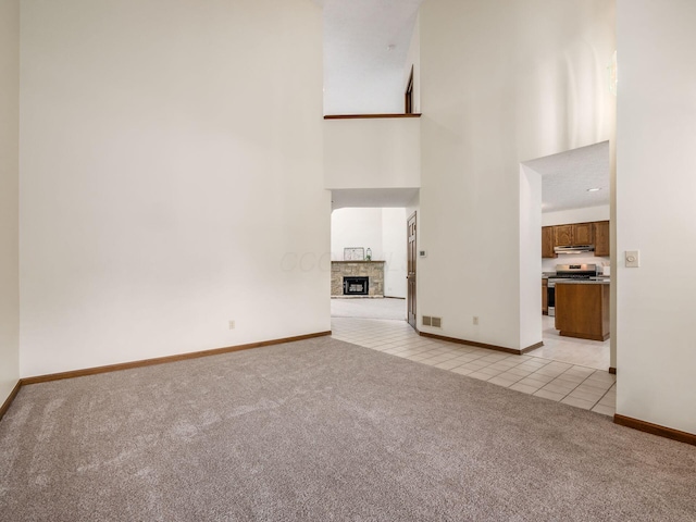 1288 Millstone Sq, Westerville, OH 43081 - unfurnished living room with light carpet, a high ceiling, light tile patterned floors, baseboards, and a fireplace with raised hearth