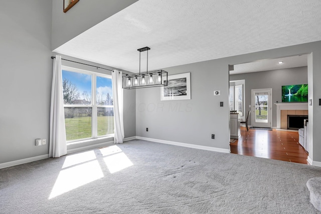 9556 Ireland Ct, Powell, OH 43065 - unfurnished dining area featuring carpet floors, baseboards, a textured ceiling, a fireplace, and a chandelier