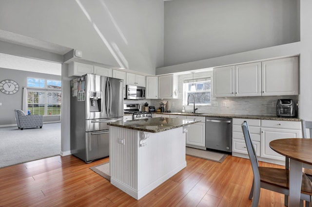 9556 Ireland Ct, Powell, OH 43065 - kitchen with appliances with stainless steel finishes, a sink, a kitchen island, tasteful backsplash, and high vaulted ceiling