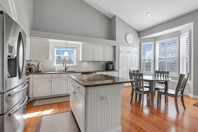 9556 Ireland Ct, Powell, OH 43065 - kitchen with stainless steel refrigerator with ice dispenser, a sink, high vaulted ceiling, a center island, and tasteful backsplash