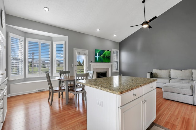 9556 Ireland Ct, Powell, OH 43065 - kitchen featuring open floor plan, ceiling fan, recessed lighting, a tiled fireplace, and light wood finished floors