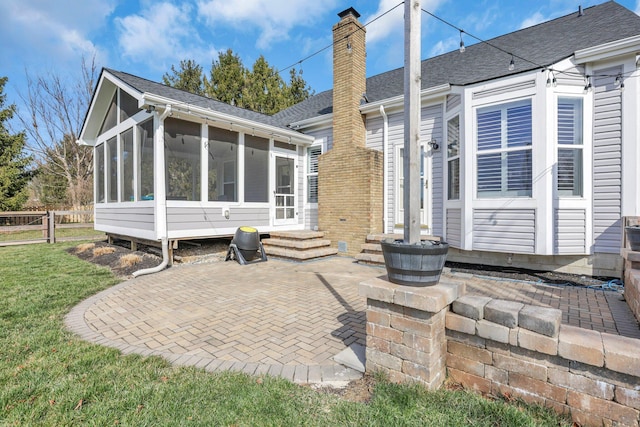 9556 Ireland Ct, Powell, OH 43065 - rear view of property featuring a sunroom, a chimney, a patio area, a shingled roof, and entry steps