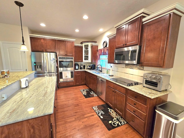 8701 Creekwood Pl, Canal Winchester, OH 43110 - kitchen with appliances with stainless steel finishes, decorative backsplash, wood finished floors, a sink, and light stone countertops