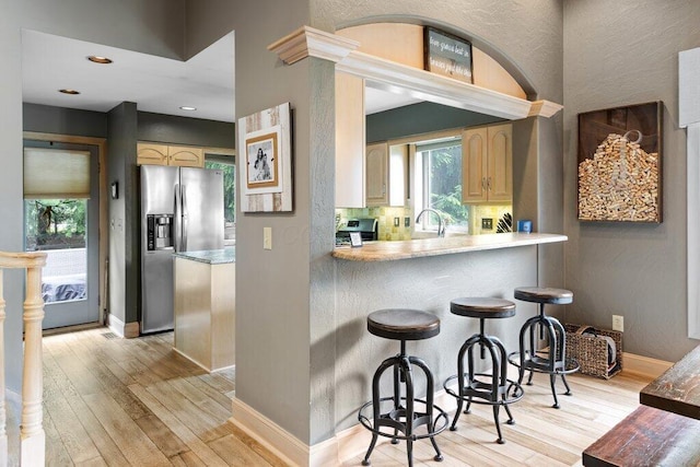 4367 Tavistock Cir, Powell, OH 43065 - kitchen featuring appliances with stainless steel finishes, light wood-style floors, a kitchen breakfast bar, baseboards, and recessed lighting