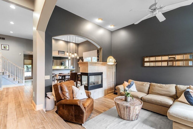 4367 Tavistock Cir, Powell, OH 43065 - living area featuring a towering ceiling, light wood-style flooring, a ceiling fan, stairway, and a fireplace