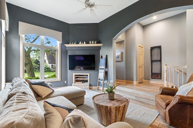4367 Tavistock Cir, Powell, OH 43065 - living area featuring arched walkways, a ceiling fan, light wood-style flooring, and baseboards