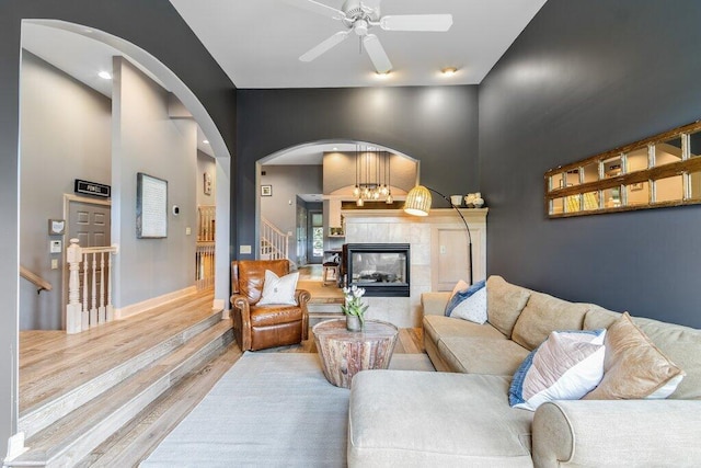 4367 Tavistock Cir, Powell, OH 43065 - living room with arched walkways, wood finished floors, ceiling fan, a tiled fireplace, and stairs