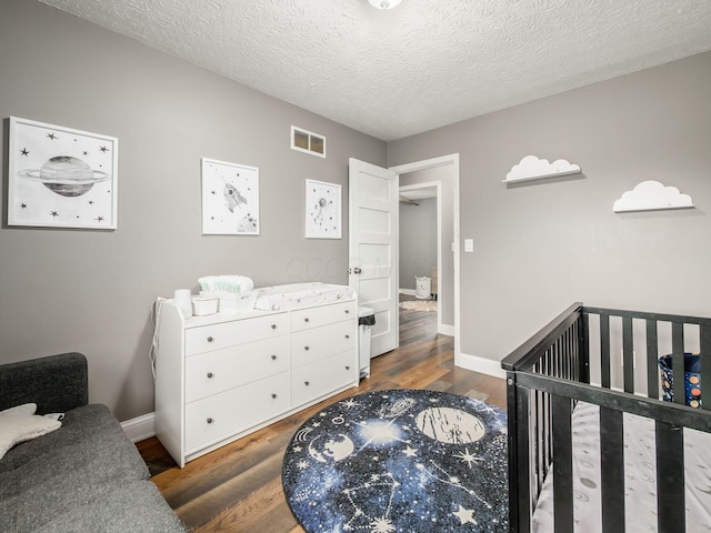 7121 Briarcliff Rd, Reynoldsburg, OH 43068 - bedroom featuring wood finished floors, baseboards, a crib, and a textured ceiling