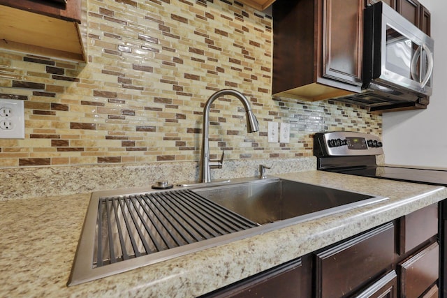 269 N 30th St, Newark, OH 43055 - kitchen with appliances with stainless steel finishes, a sink, light countertops, dark brown cabinetry, and tasteful backsplash