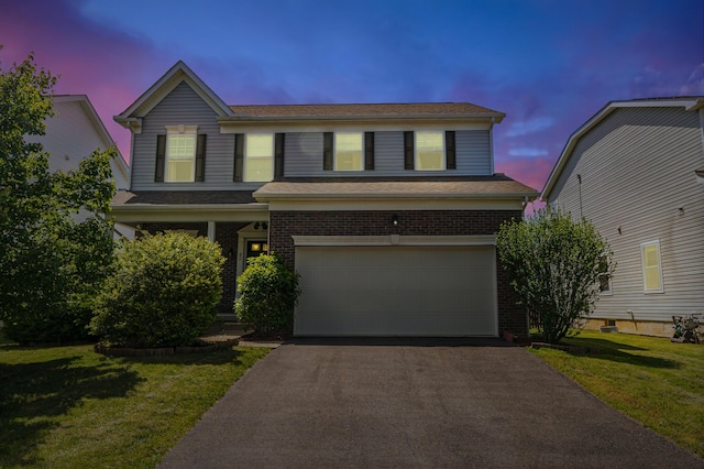 42 Carolyn Ln, Delaware, OH 43015 - traditional-style house with an attached garage, asphalt driveway, brick siding, and a lawn
