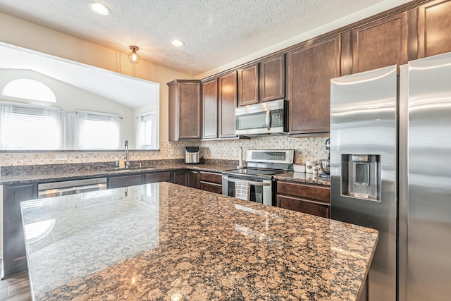 42 Carolyn Ln, Delaware, OH 43015 - kitchen featuring appliances with stainless steel finishes, a sink, lofted ceiling, backsplash, and dark stone countertops