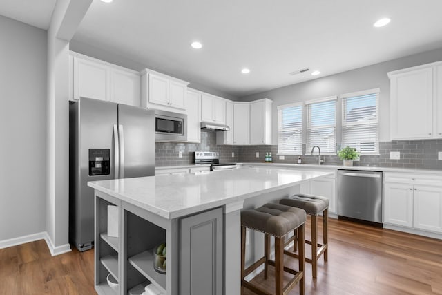 6051 Limewood Dr, Westerville, OH 43081 - kitchen featuring appliances with stainless steel finishes, under cabinet range hood, a center island, backsplash, and recessed lighting