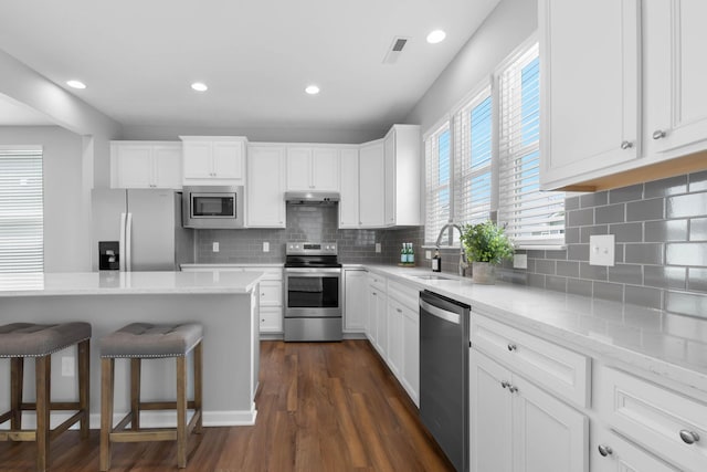 6051 Limewood Dr, Westerville, OH 43081 - kitchen with stainless steel appliances, a sink, under cabinet range hood, a breakfast bar area, and dark wood-style flooring