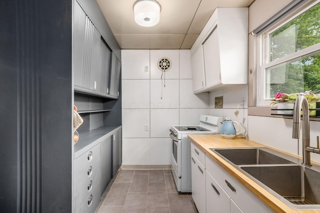 214 Arden Rd, Columbus, OH 43214 - kitchen with white electric range oven, a sink, white cabinetry, light tile patterned flooring, and light countertops