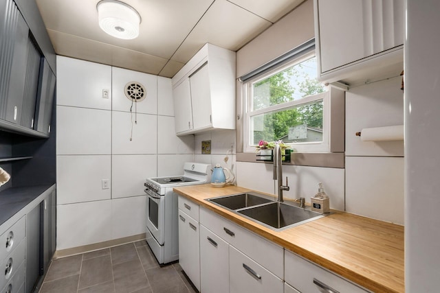 214 Arden Rd, Columbus, OH 43214 - kitchen with white electric range oven, a sink, white cabinetry, butcher block countertops, and dark tile patterned flooring