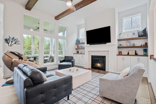 1526 Villa Way, Powell, OH 43065 - living room featuring light wood finished floors, a glass covered fireplace, beam ceiling, a ceiling fan, and built in shelves