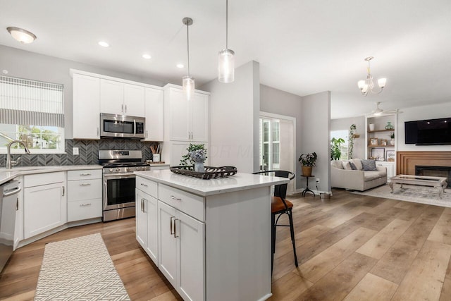 7306 Whimbrel Ln, Sunbury, OH 43074 - kitchen featuring stainless steel appliances, a sink, open floor plan, a kitchen island, and decorative backsplash
