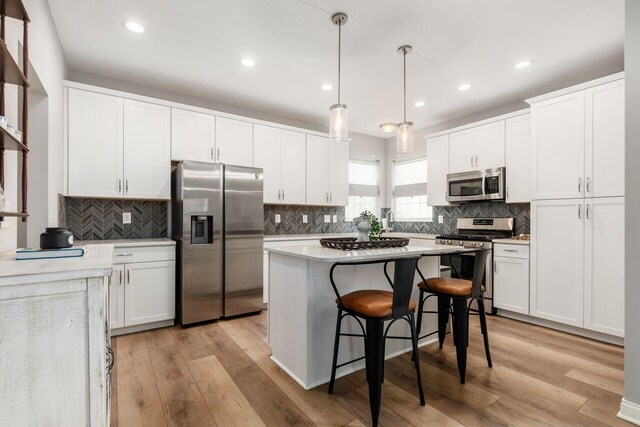 7306 Whimbrel Ln, Sunbury, OH 43074 - kitchen with stainless steel appliances, a kitchen island, decorative backsplash, white cabinetry, and recessed lighting