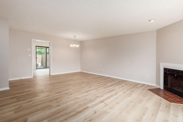 2353 Mccauley Ct Unit 6, Columbus, OH 43220 - unfurnished living room featuring a chandelier, light wood-style floors, a tile fireplace, and baseboards