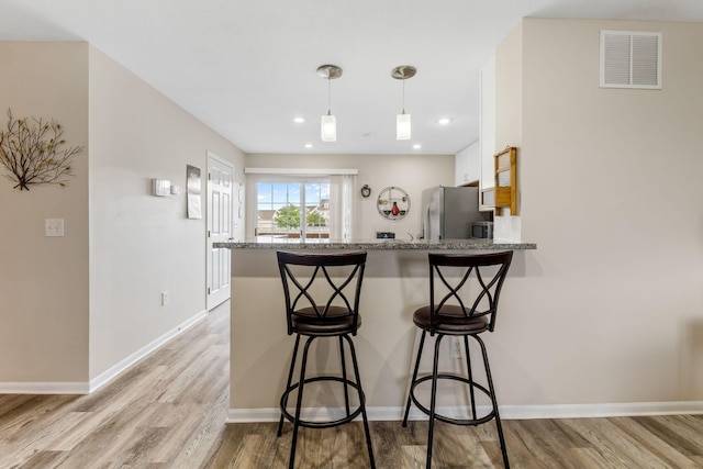 1080 Shady Lake Dr, Columbus, OH 43228 - kitchen featuring freestanding refrigerator, white cabinets, a breakfast bar, light wood-type flooring, and a peninsula