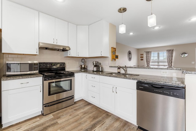 1080 Shady Lake Dr, Columbus, OH 43228 - kitchen featuring appliances with stainless steel finishes, under cabinet range hood, a sink, dark stone countertops, and a peninsula