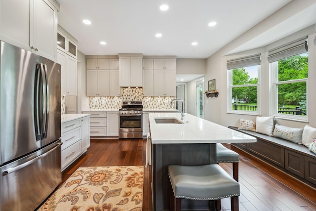 2407 Bryton Dr, Powell, OH 43065 - kitchen with stainless steel appliances, a sink, a breakfast bar, light countertops, and recessed lighting