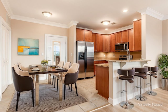 539 W 1st Ave Unit 308, Columbus, OH 43215 - kitchen with stainless steel appliances, crown molding, a peninsula, a breakfast bar, and light tile patterned flooring
