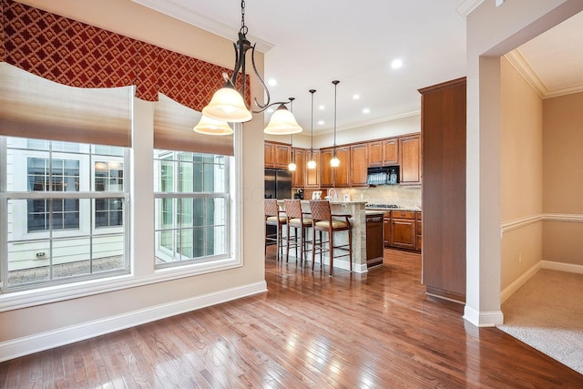 6711 Cooperstone Dr, Dublin, OH 43017 - kitchen featuring ornamental molding, black microwave, baseboards, brown cabinets, and a kitchen bar