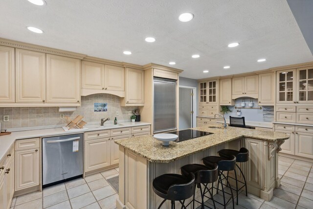5210 Chevy Chase Ct, Columbus, OH 43220 - kitchen with appliances with stainless steel finishes, light tile patterned floors, tasteful backsplash, a kitchen island with sink, and light stone counters