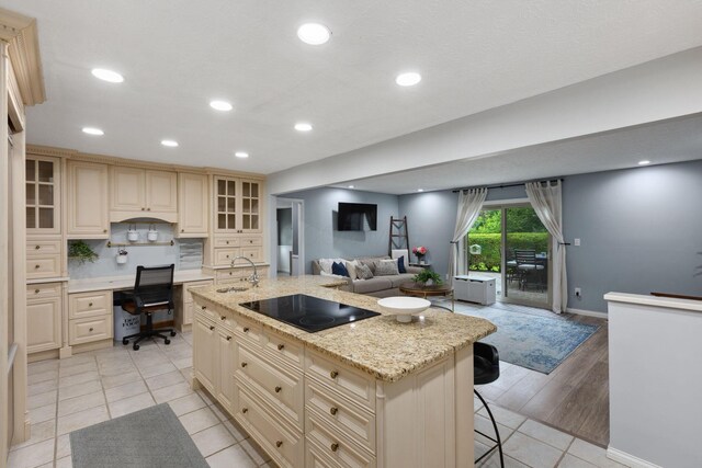 5210 Chevy Chase Ct, Columbus, OH 43220 - kitchen featuring black electric cooktop, cream cabinets, light tile patterned floors, open floor plan, and a center island with sink