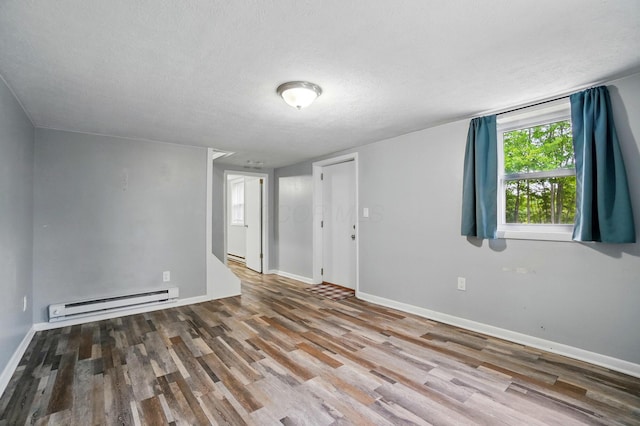 8301 Bennington Chapel Rd, Centerburg, OH 43011 - empty room featuring a baseboard heating unit, wood finished floors, baseboards, and a textured ceiling