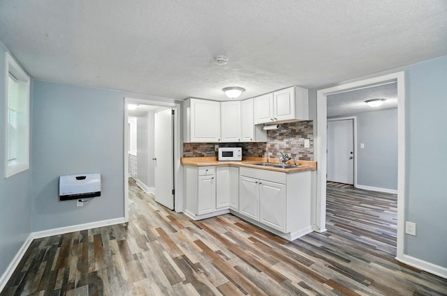 8301 Bennington Chapel Rd, Centerburg, OH 43011 - kitchen with white microwave, a sink, white cabinets, wood finished floors, and a textured ceiling