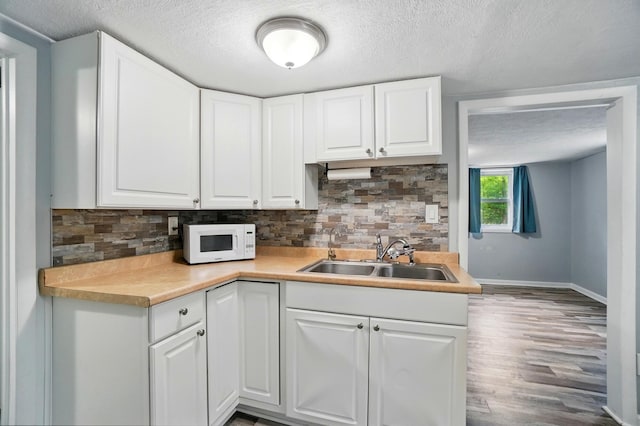 8301 Bennington Chapel Rd, Centerburg, OH 43011 - kitchen featuring a sink, white microwave, tasteful backsplash, a textured ceiling, and white cabinets