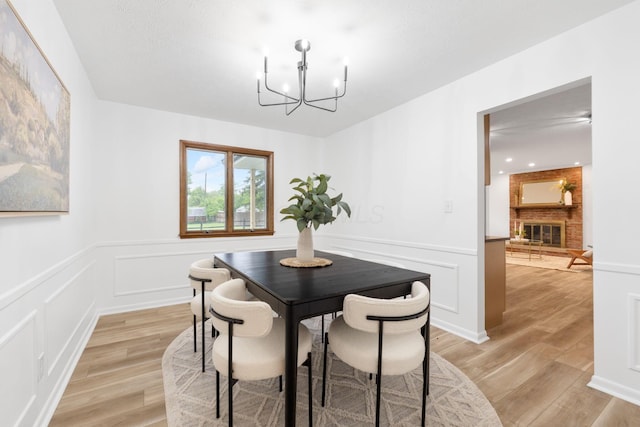 5148 Riverbirch Dr N, Columbus, OH 43229 - dining area featuring a chandelier, light wood-style flooring, wainscoting, a decorative wall, and a fireplace