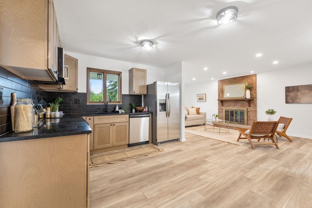 5148 Riverbirch Dr N, Columbus, OH 43229 - kitchen featuring stainless steel appliances, dark countertops, light wood finished floors, decorative backsplash, and a sink