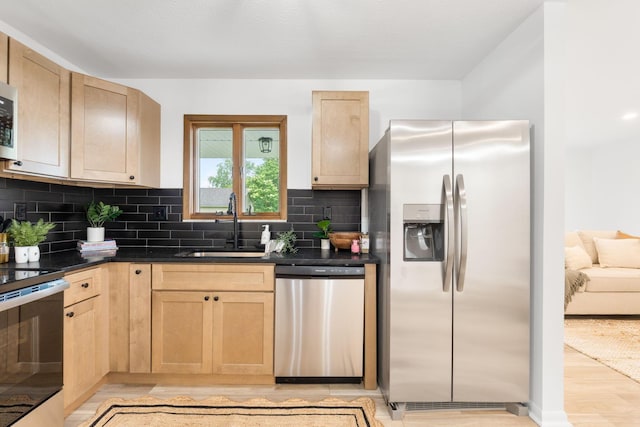 5148 Riverbirch Dr N, Columbus, OH 43229 - kitchen with stainless steel appliances, a sink, light brown cabinetry, light wood-style flooring, and dark countertops