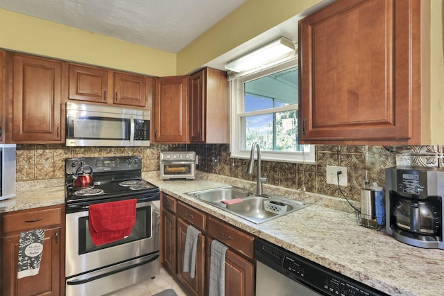 5042 Lindora Dr, Columbus, OH 43232 - kitchen with stainless steel appliances, a sink, decorative backsplash, and brown cabinets