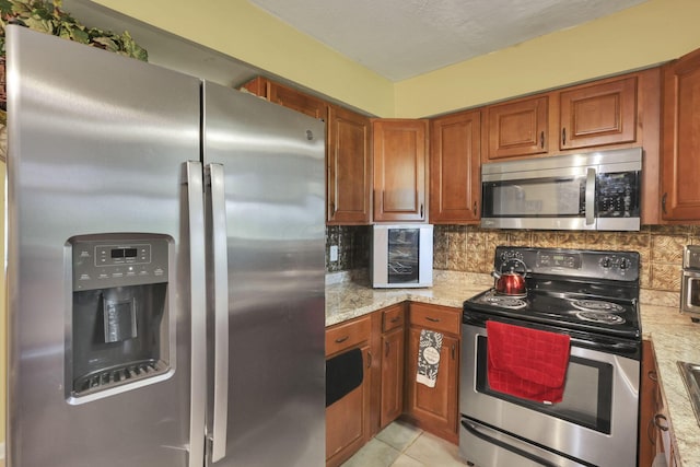 5042 Lindora Dr, Columbus, OH 43232 - kitchen featuring appliances with stainless steel finishes, brown cabinets, backsplash, and light stone counters