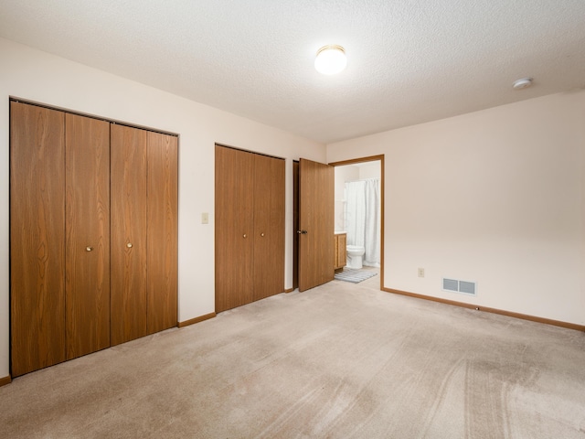 2594 Roberts Ct, Hilliard, OH 43026 - unfurnished bedroom with two closets, light colored carpet, baseboards, connected bathroom, and a textured ceiling